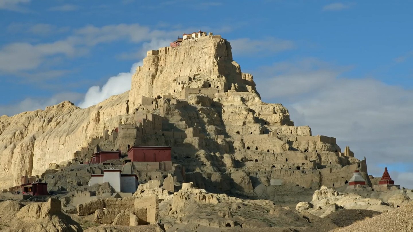 Buildings on a steep, rocky hill. Programme still.
