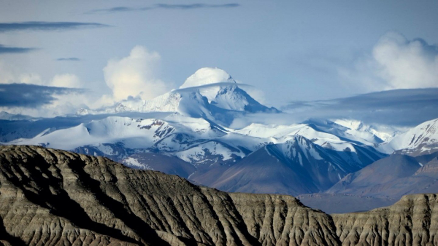 A snow-covered peak beyond the ridges. Programme still.