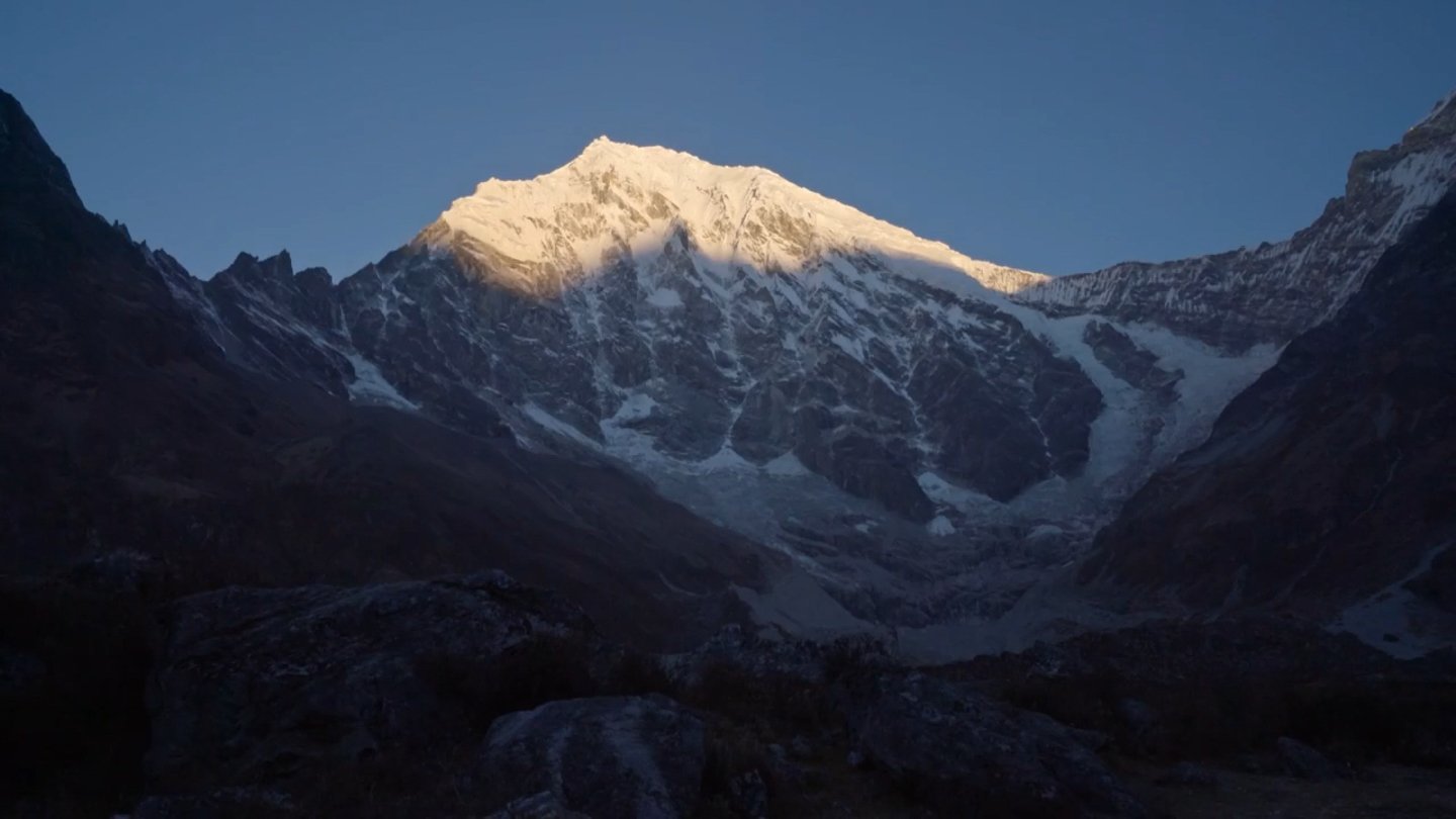 A sunlit snow peak above shaded slopes. Programme still.