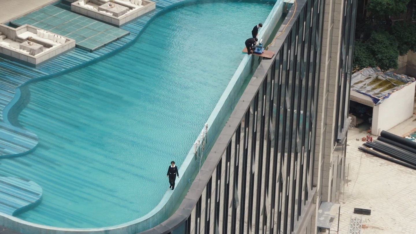 Workers beside an elevated swimming pool.