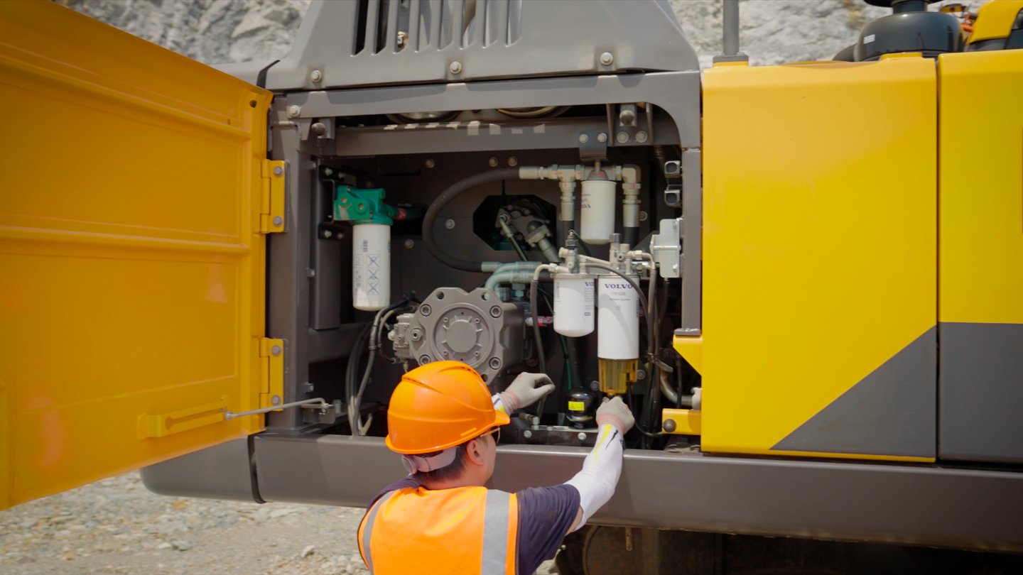 Production technician standing beside the Volvo EC360 excavator