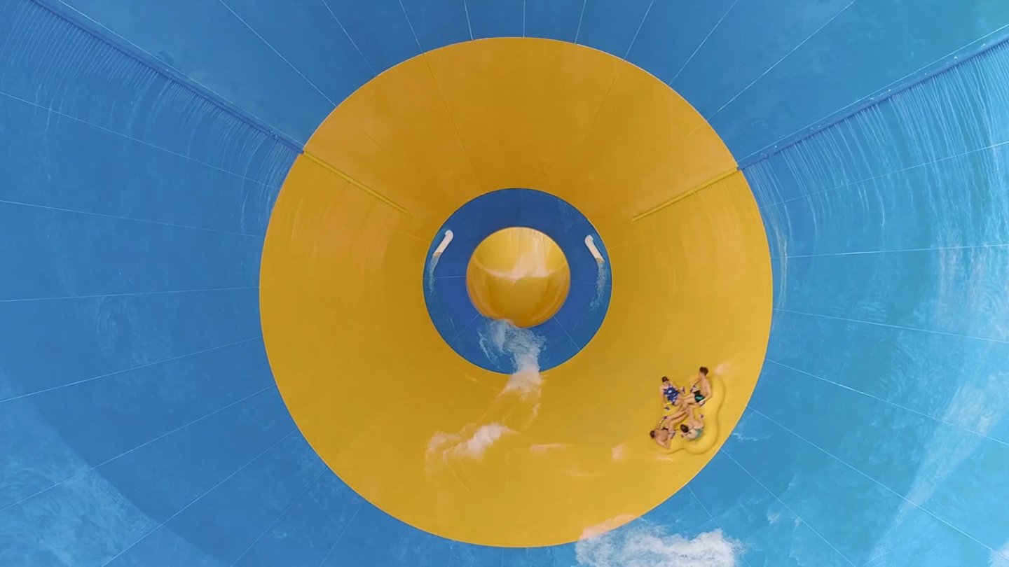 Riders descending a blue and yellow waterslide.