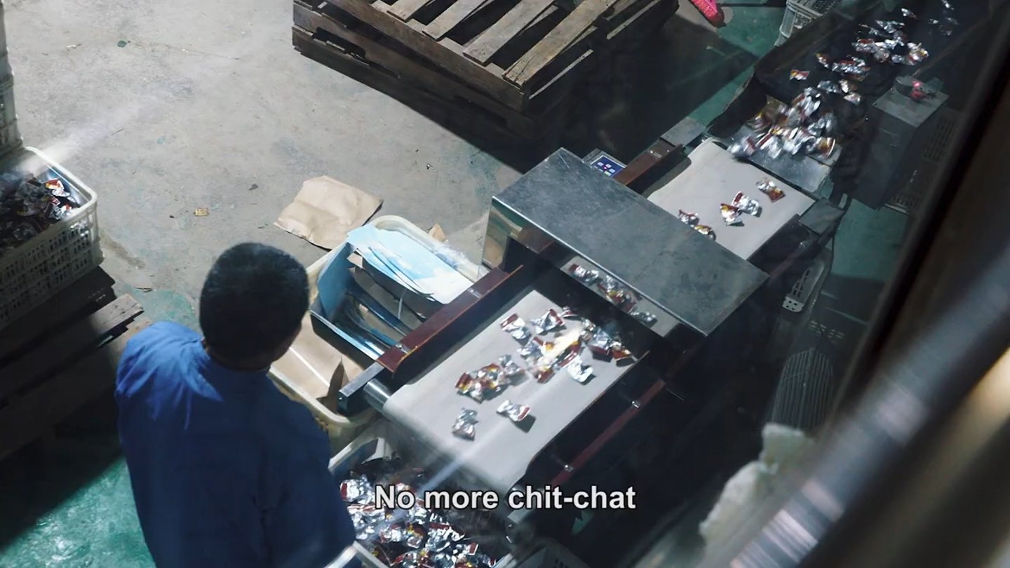 Material moving along a conveyor, with dialogue subtitled in the trailer. Frame from Ascension.
