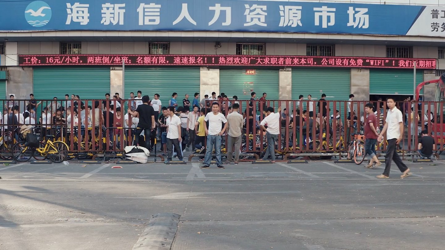 People waiting outside the Haixinxin labour market. Frame from the Ascension trailer.