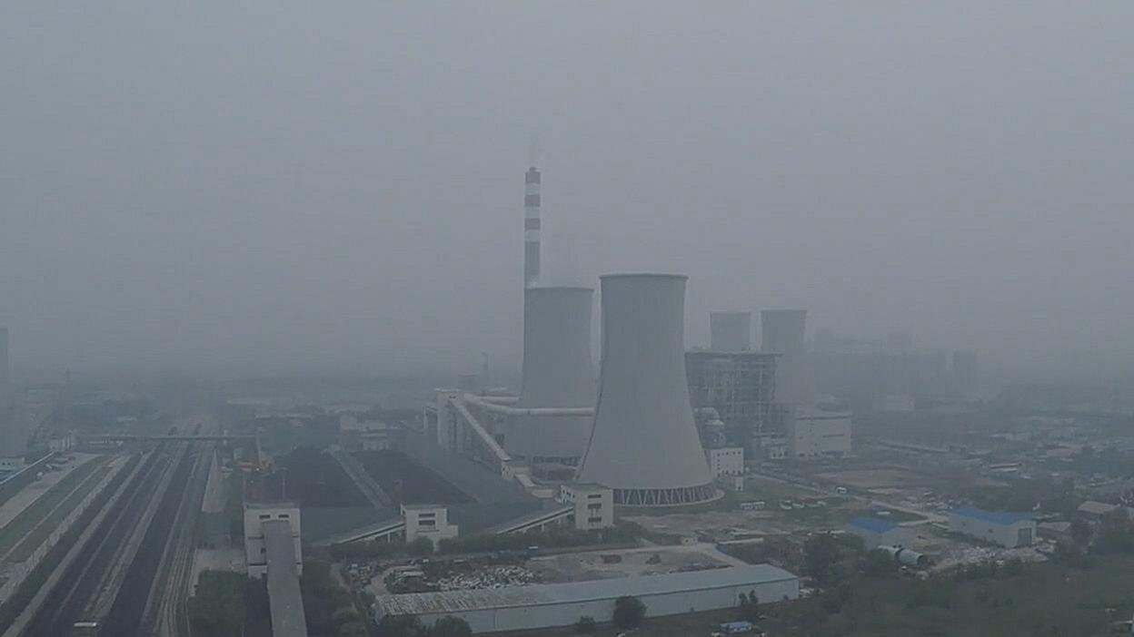 Cooling towers and rail lines beneath a hazy sky. Film still.