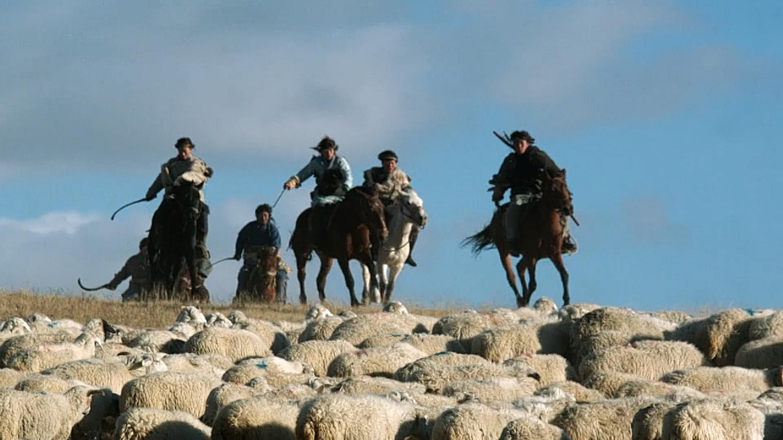 Mounted riders crossing rocky ground in a historical re-enactment.