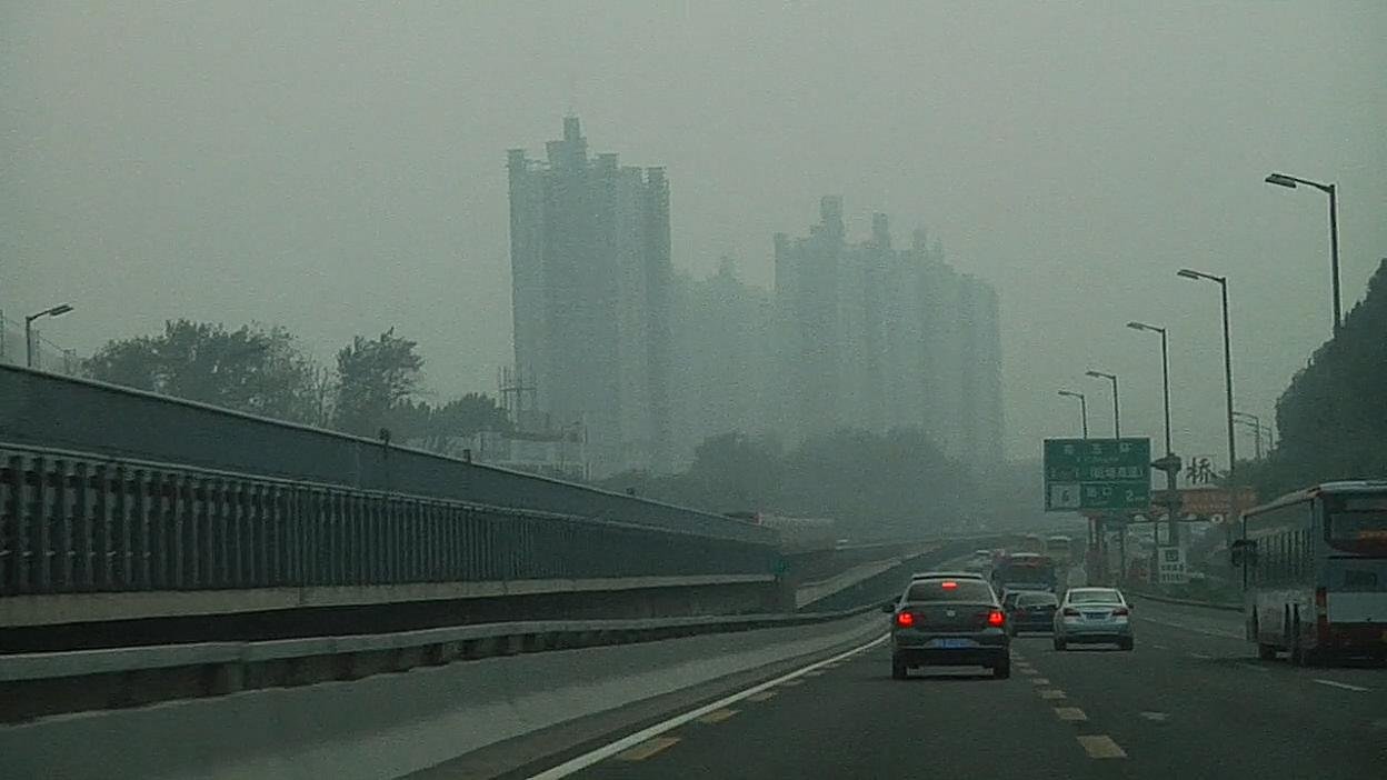 A road approaching a hazy city skyline. Film still.