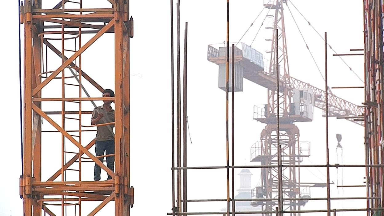 A person within the steel framework of a crane. Film still.