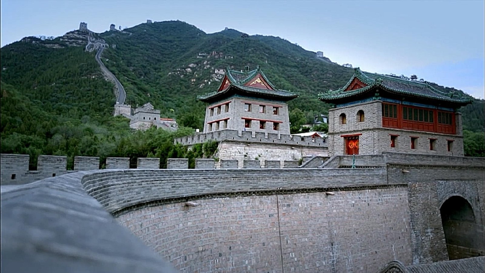 Fortified gateways and the wall climbing the hillside behind them.