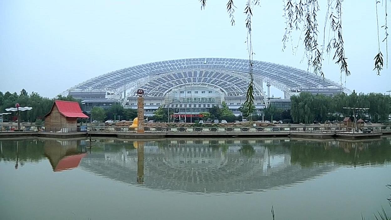 An arched building reflected in water. Film still.