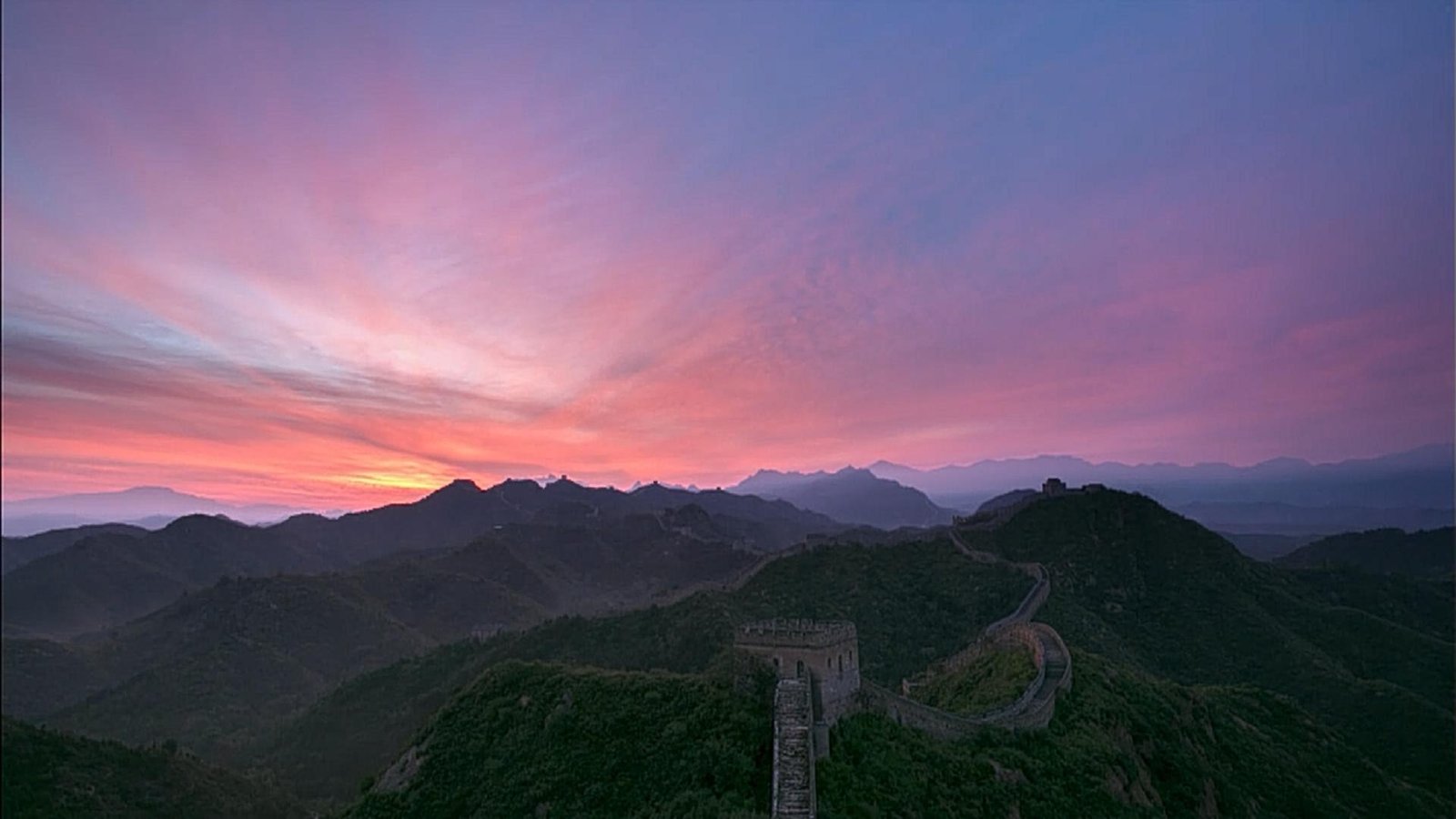 Pink evening light above a mountain section of the wall.
