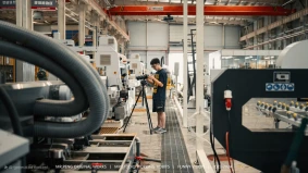 Film crew shooting in a Shanghai factory with industrial equipment in the background.