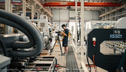 Film crew shooting in a Shanghai factory with industrial equipment in the background.