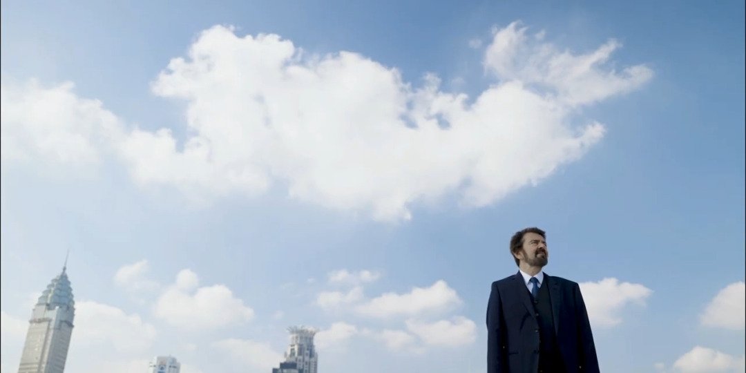 Man in a business suit standing beneath Shanghai’s skyline, symbolizing leadership and vision in video production in China.
