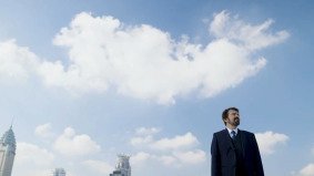 Man in a business suit standing beneath Shanghai’s skyline, symbolizing leadership and vision in video production in China.