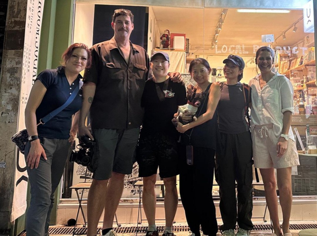 Fixer from Alchemist Films posing with TV video crew in front of a shop under Hong Kong’s Monster Building after a successful shoot — expert China fixer video production support