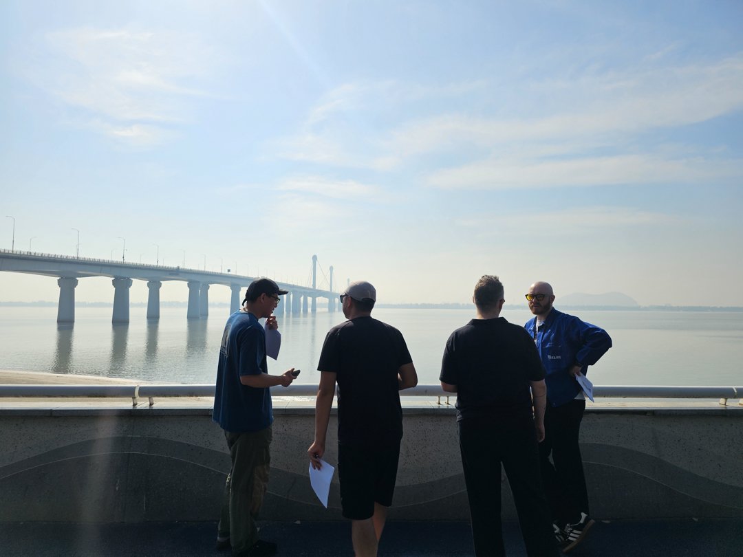 Chinese and American directors with a local film crew in Hangzhou, scouting locations by a beautiful river and bridge — supported by Alchemist Films China fixer video production services