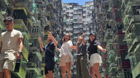 Local producer and German TV crew smiling together in a group photo at the Monster Building in Hong Kong after a smooth and efficient video production supported by Alchemist Films