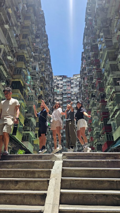 Local producer and German TV crew smiling together in a group photo at the Monster Building in Hong Kong after a smooth and efficient video production supported by Alchemist Films