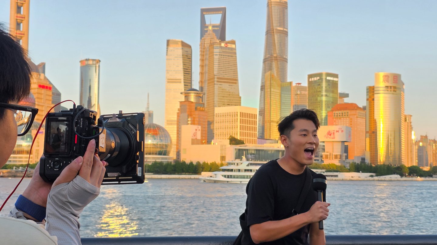 Host with camera and Shanghai skyline during golden hour - Alchemist Films BTS